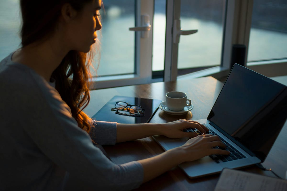 a woman sitting at a desk using a laptop using the usenet